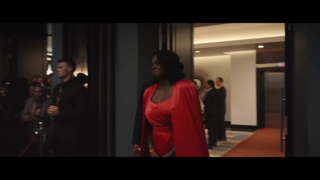 Viola Davis in een rode jurk loopt een hotelgang in, in een still uit de trailer van haar film G20