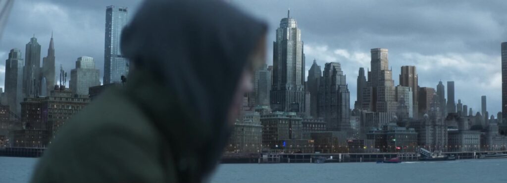 Figuur in capuchon voor de skyline van Gotham City in de film Clayface