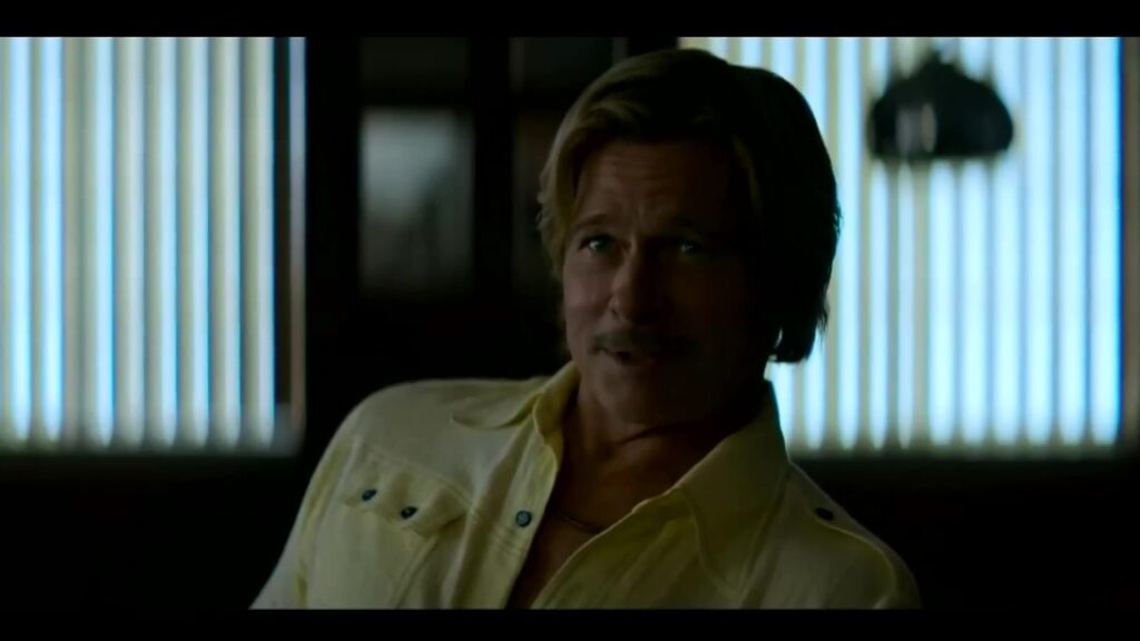 Brad Pitt als Cliff Booth in een geel overhemd in de trailer van The Further Mis-Adventures of Cliff Booth