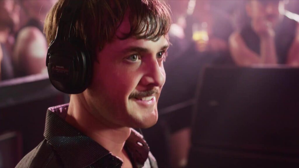 Een jonge dj met koptelefoon in een volle discotheek in de film Downtown