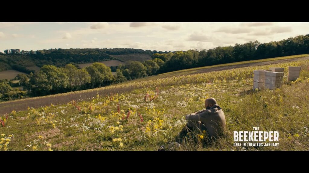 Jason Statham zit tussen bijenkasten in een bloemenveld in The Beekeeper
