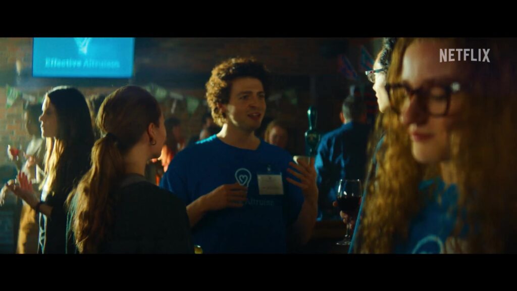 Anthony Boyle en Julia Garner op een bijeenkomst in de officiële trailer van The Altruists