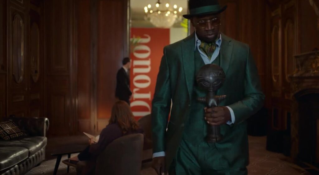 Omar Sy als Assane Diop in een groen pak bij veilinghuis Drouot in Lupin deel 4