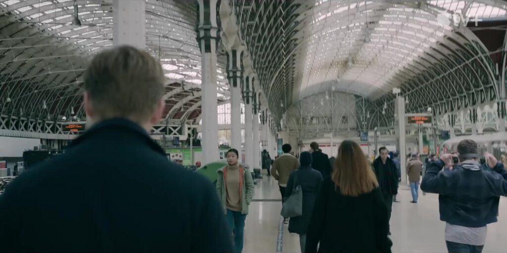 Een man loopt in een trailerbeeld van de spionageserie Slow Horses door een druk Londens station