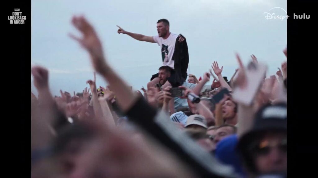 Fans op elkaars schouders tijdens een concert van Oasis in de trailer van Don't Look Back In Anger