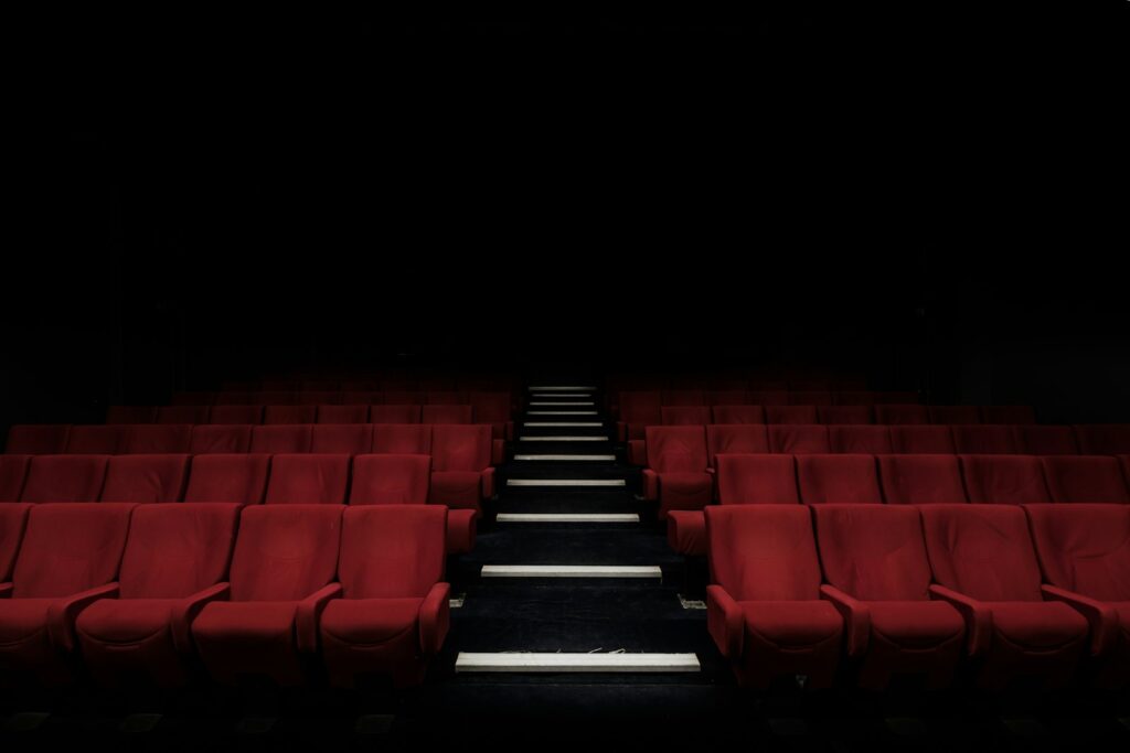 Rijen rode bioscoopstoelen in een donkere filmzaal