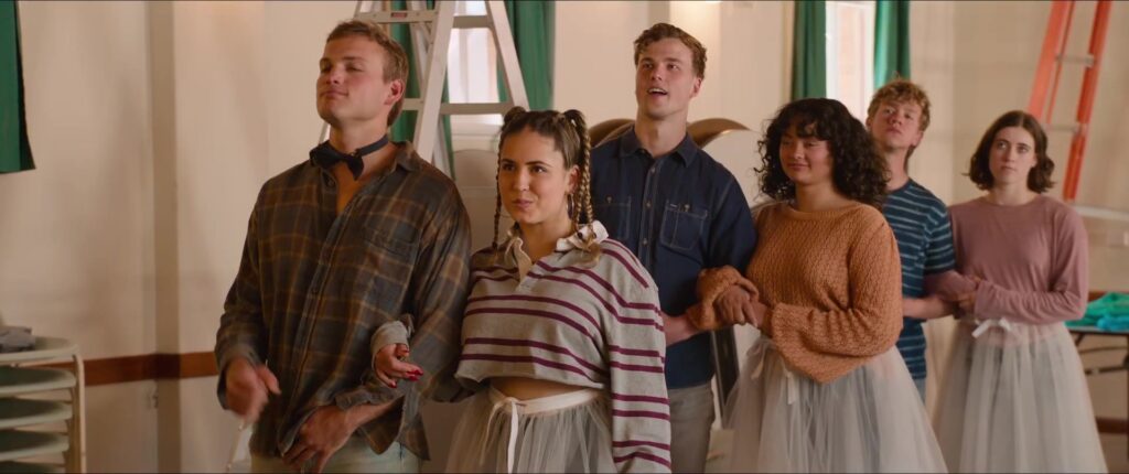 Jongeren in tule rokken en geruite overhemden in een zaaltje in de trailer van The Deb