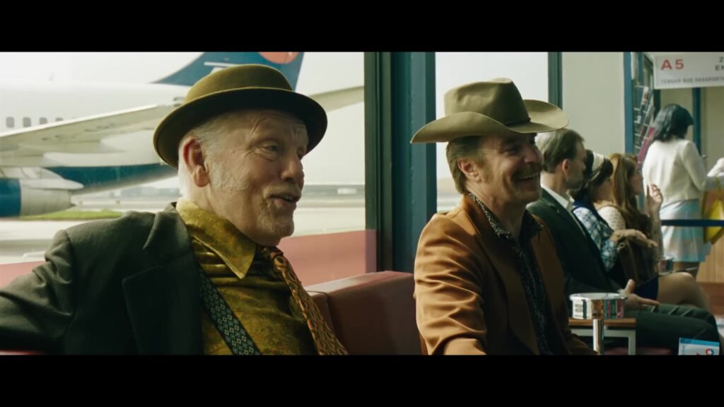 John Malkovich en Sam Rockwell met hoeden in een vertrekhal in een still uit de trailer van Wild Horse Nine