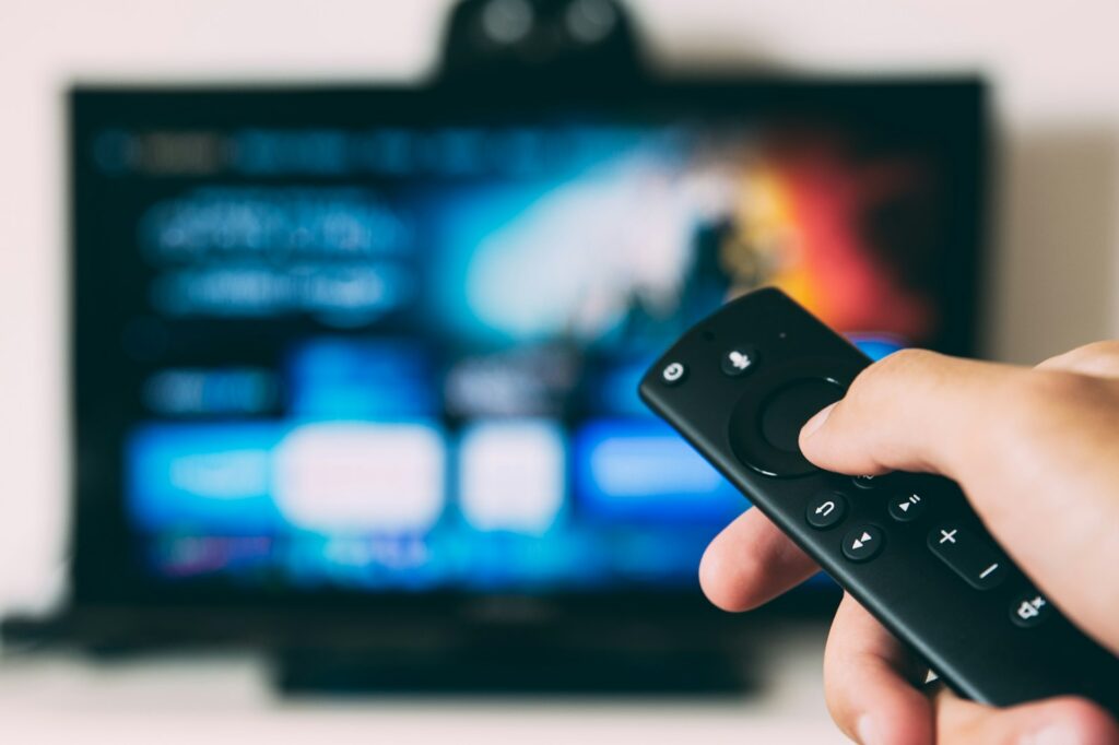 Iemand kiest met de afstandsbediening een programma in de Netflix-app op een televisie
