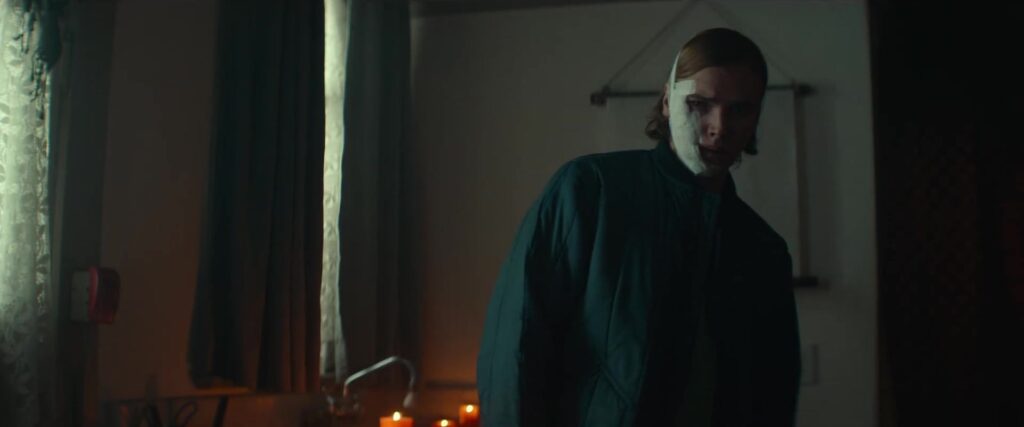 Spookhuisacteur met een half wit masker in een schemerig huis in de trailer van Slayground