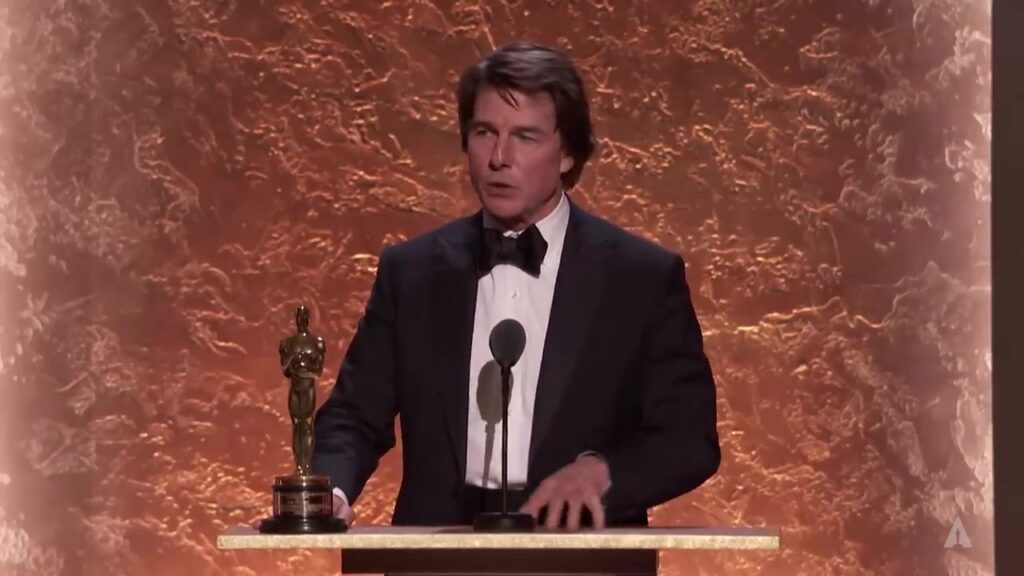 Tom Cruise in smoking achter een spreekgestoelte met een Oscarbeeldje bij de Governors Awards