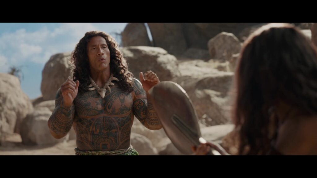 Dwayne Johnson als Maui op het strand in de live-action film Vaiana